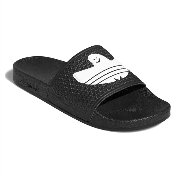 An Adidas Shmoofoil Slide Core Black/White with a white face on it.