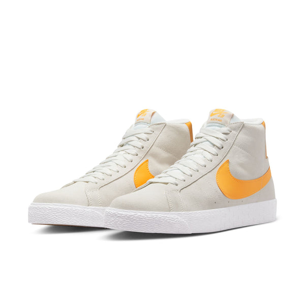 A pair of white and yellow Nike SB Blazer Mid Summit White/Laser Orange sneakers.