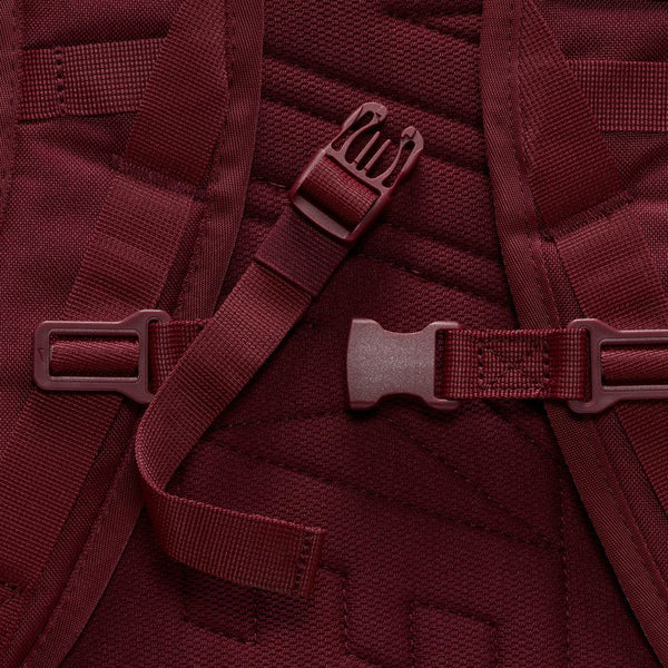 Close-up of the NIKE SB RPM BACKPACK DARK BEETROOT straps and plastic buckle by nike, highlighting its detailed fabric, harness system, and water-resistant design.