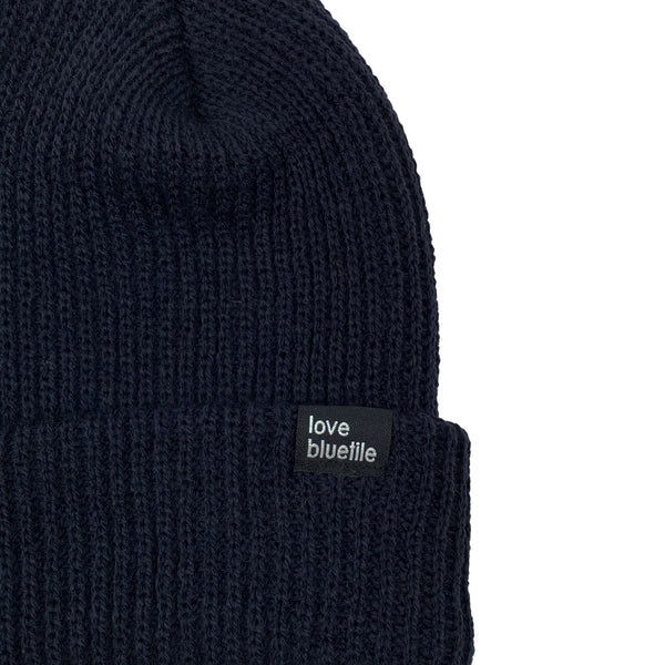 A Bluetile Skateboards navy knit beanie with the word love on it.