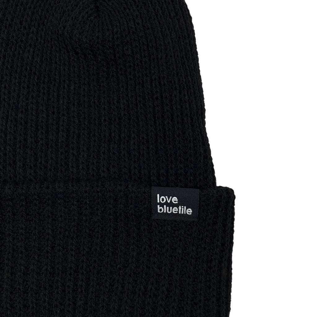 A BLUETILE LOVE ALWAYS KNIT BEANIE BLACK with a white label on it.
