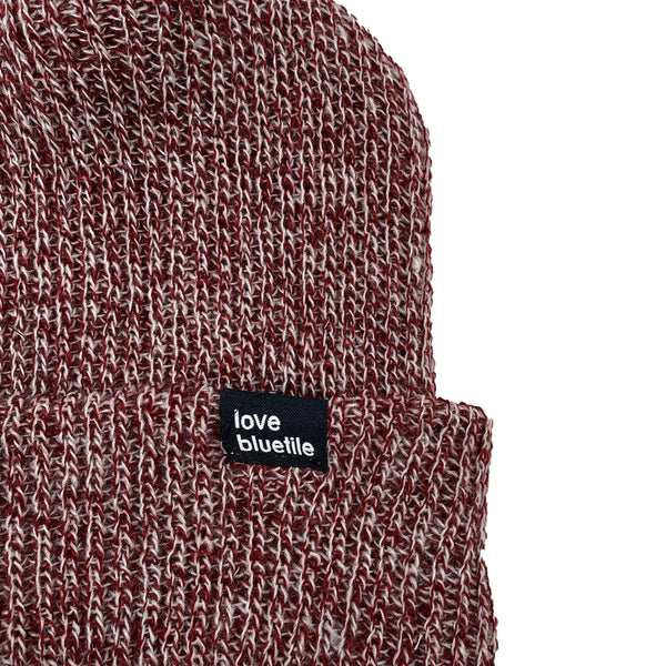 A BLUETILE LOVE ALWAYS KNIT BEANIE BURGUNDY MARBLE with a label on it.