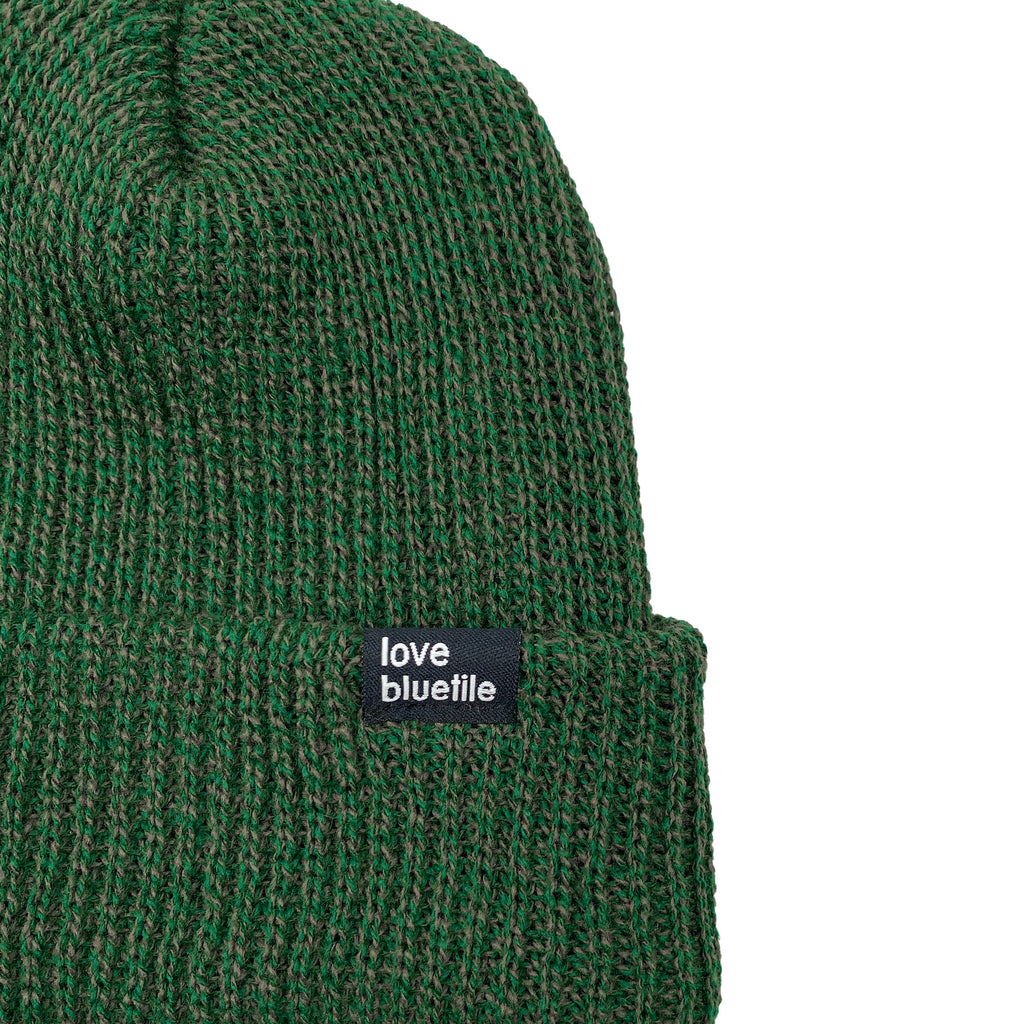 A fitted Bluetile Love Always Knit Beanie Forest/Olive Marble with a black label.