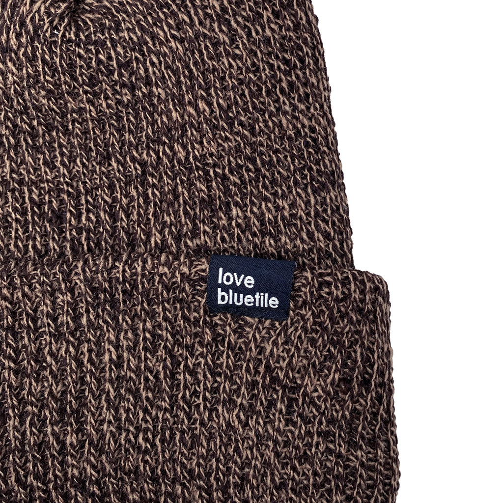 a close up of a BLUETILE LOVE ALWAYS KNIT BEANIE DARK BROWN/SAND MARBLE with a tag on it.