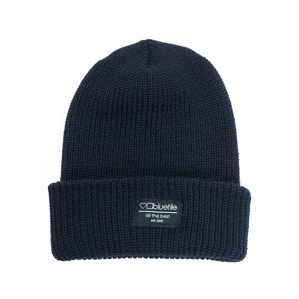 The BLUETILE SURPLUS BEANIE NAVY, also known as a surplus beanie, is showcased against a white background.