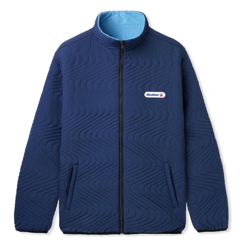 A BUTTER GOODS QUILTED REVERSIBLE JACKET NAVY/BLUE with a patch on the front.