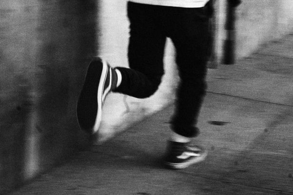 A black and white photo print of Brennan by Savannah Bockus running with a baseball bat from Bluetile Skateboards.