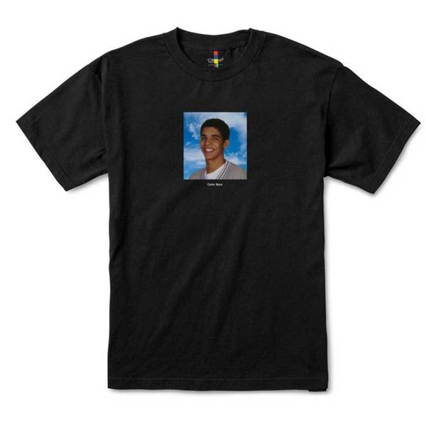 The COLOR BARS DEGRASSI YEARBOOK TEE BLACK, by COLOR BARS, showcases a centered printed image of a smiling person set against a blue sky background, reflecting the iconic DEGRASSI style.