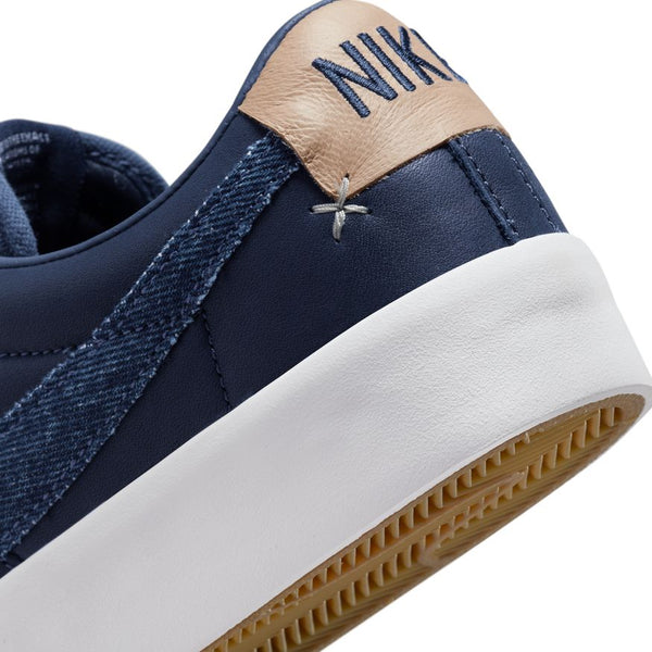 Close-up image of a nike NIKE SB BLAZER LOW PRO GT MIDNIGHT NAVY / WHITE with brown detailing and a white sole, showcasing the Nike logo on the heel.