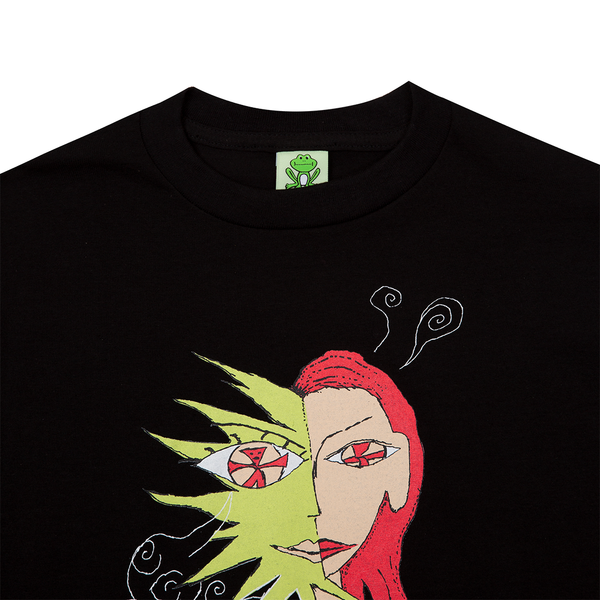 The FROG DISTRACTED TEE BLACK by FROG features a stylized, abstract graphic of a face divided into two halves: one green with swirling lines, and the other red with straight hair. A small green frog icon at the collar adds a playful touch.