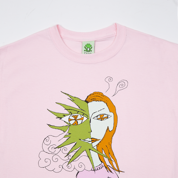 The FROG DISTRACTED TEE PINK from FROG is a light pink t-shirt featuring a graphic of a woman's face merged with abstract shapes and patterns, perfect for those who like to stand out.