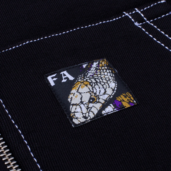 Close-up of black Brushed Back Cotton Fleece with white stitching, featuring a patch with a snake illustration and partial "FA" letters. Inspired by the FUCKING AWESOME LESSER GOD ZIP UP HOODIE BLACK from FUCKING AWESOME.