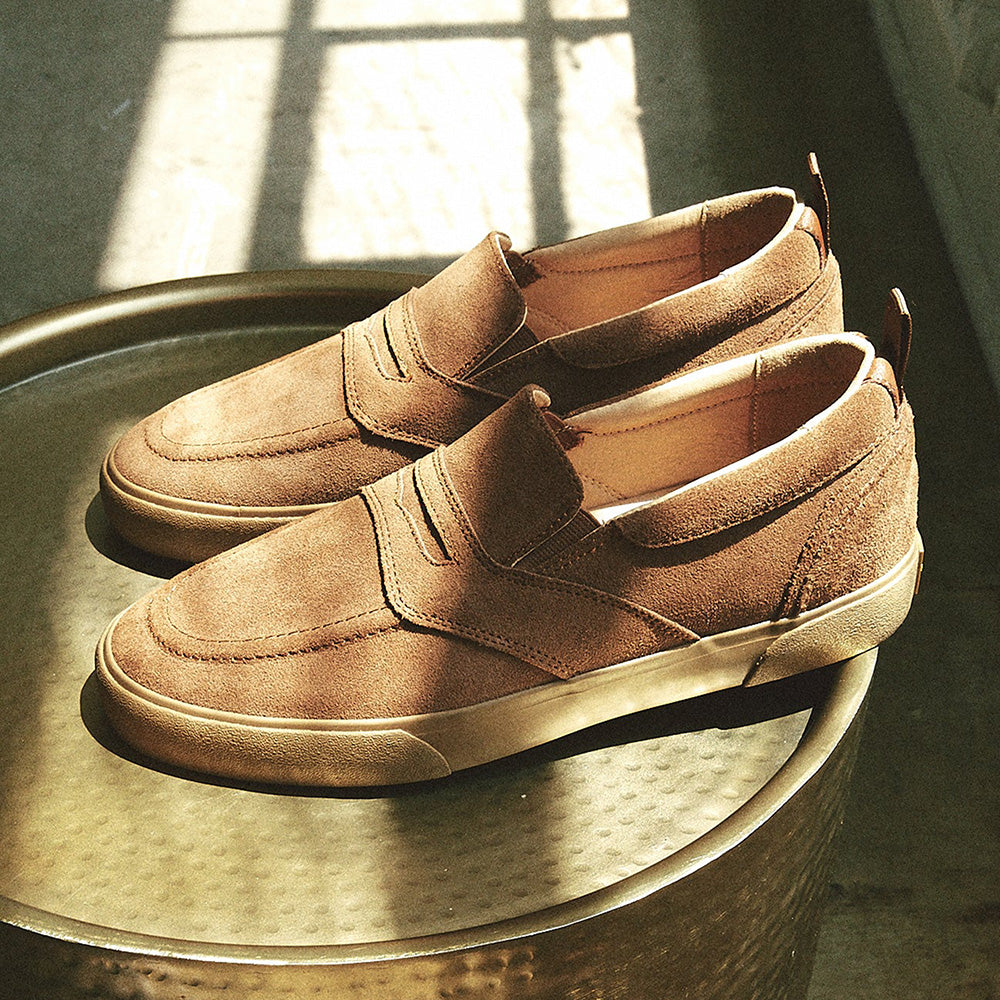 A pair of HOURS IS YOURS brown suede slip on shoes with a vulcanized outsole.