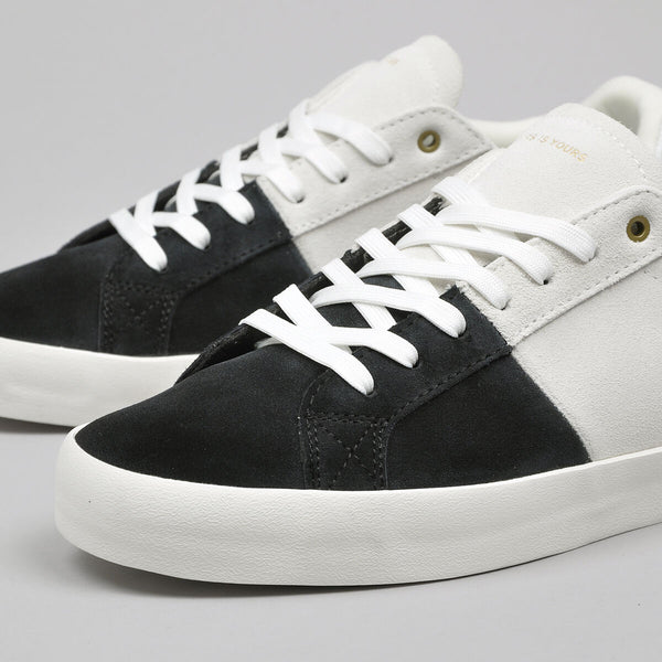 A pair of HOURS IS YOURS black and white sneakers with a HOURS IS YOURS black/white two-tone suede upper and white soles.