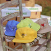Four Bluetile Skateboards hats sitting on a wooden chair.