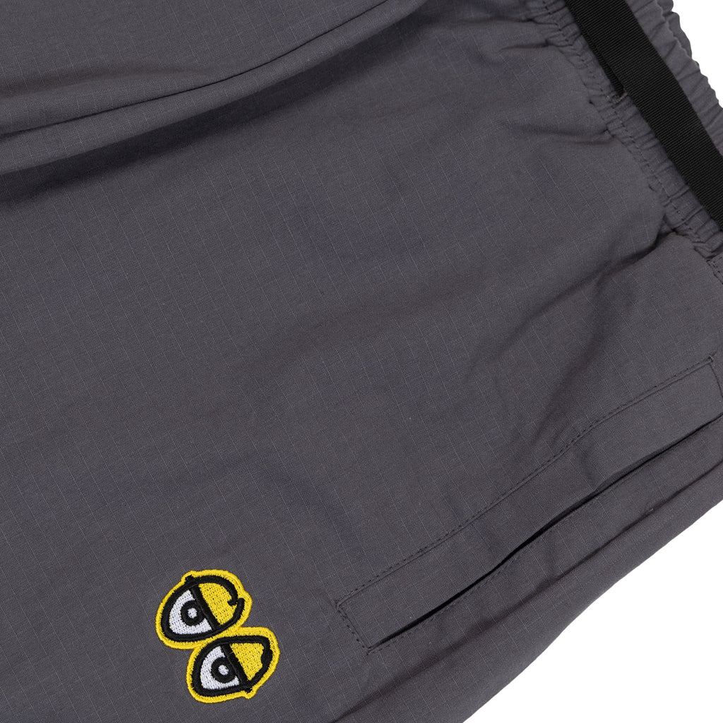 A close up of a pair of Deluxe's Krooked Eyes pants in charcoal and yellow.