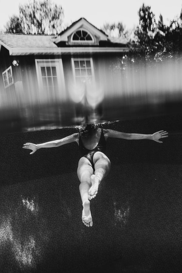 A black and white photo print of Savannah Bockus swimming in the Water Signs by Savannah Bockus near a house.