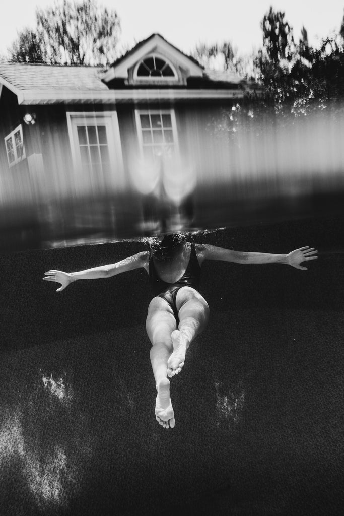A black and white photo print of Savannah Bockus swimming in the Water Signs by Savannah Bockus near a house.