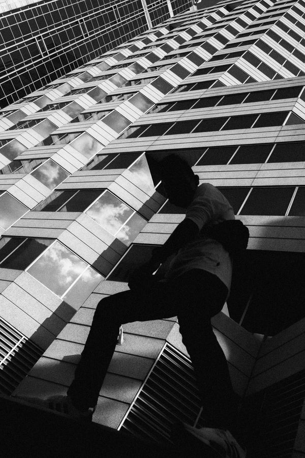 A black and white photo of Nathan by Savannah Bockus on a building, taken with a Bluetile Skateboards