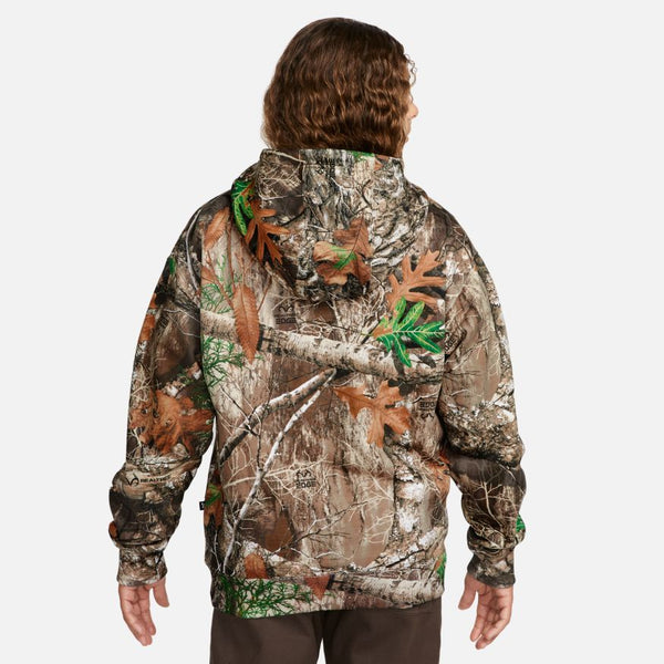 A man wearing a nike NIKE SB x REALTREE® FLEECE ALLOVER CAMO HOODIE and brown pants.