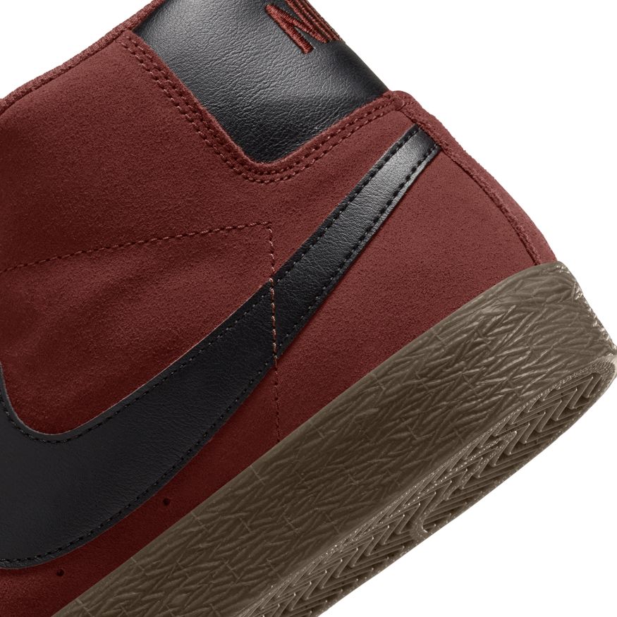 A pair of red and black Nike SB Blazer Mid Oxen Brown/Black sneakers.