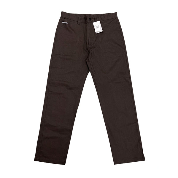 A pair of NIKE SB ISHOD PANTS BROWN from nike, featuring a button and zipper closure. Displayed flat with tags attached near the waistband, these pants are crafted from durable woven fabric with extra stitching for added durability.