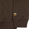 Close-up of the NIKE SB OSKI ORANGE LABEL HOODIE BROWN by nike, featuring a small sewn rectangular Orange Label with Nike SB and OSKI logos near the pocket and cuff.
