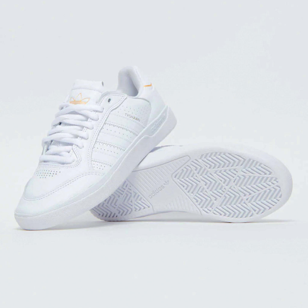 A pair of ADIDAS TYSHAWN LOW WHITE / WHITE / GOLD sneakers with white uppers and orange soles.