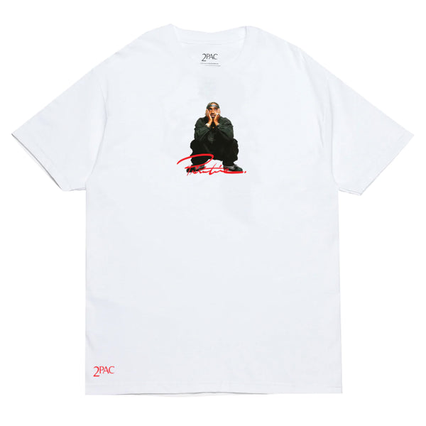 PRIMITIVE X TUPAC SHAKUR TEE WHITE featuring an image of Tupac Shakur with hands clasped near his face, wearing a bandana, and the word "2PAC" in red text below the image.