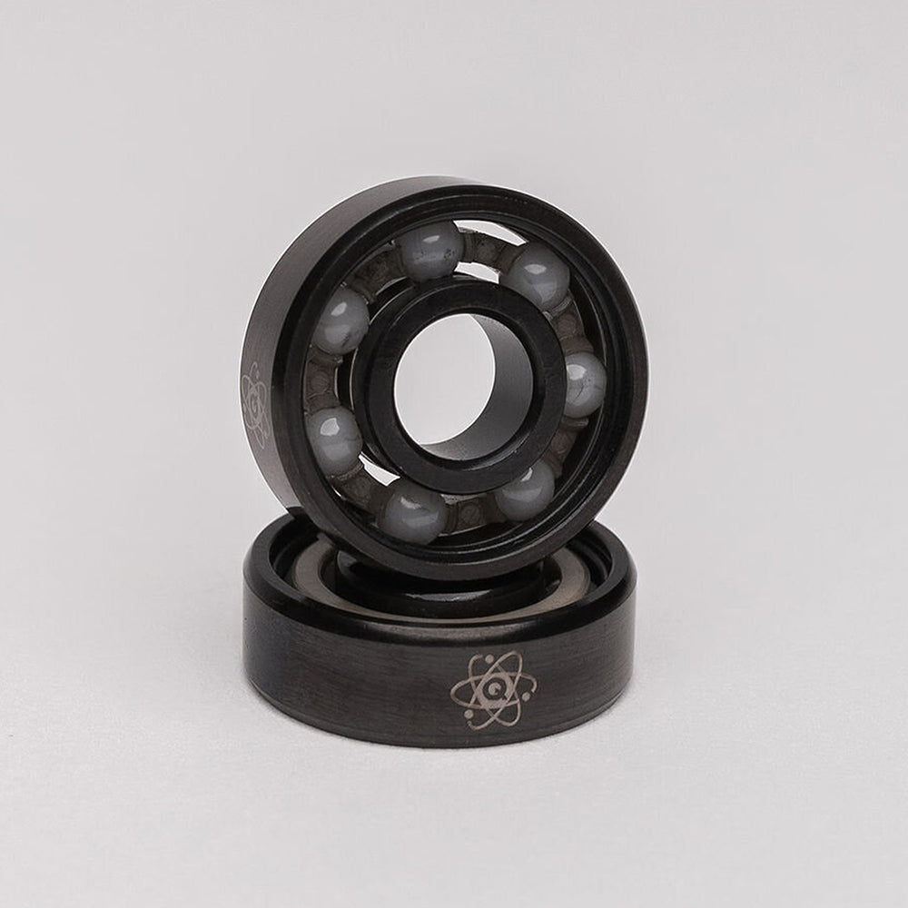 A pair of QUANTUM ISOTOPES CERAMIC HYBRID BEARINGS, known for their high tensile strength, featured on a white background. (Brand Name: Quantum Bearings)