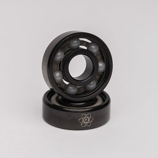A pair of QUANTUM ISOTOPES CERAMIC HYBRID BEARINGS, known for their high tensile strength, featured on a white background. (Brand Name: Quantum Bearings)