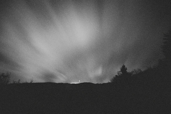 A black and white photo print of the aurora over a hill at night, Night by Shawn Gerald, from Bluetile Skateboards.
