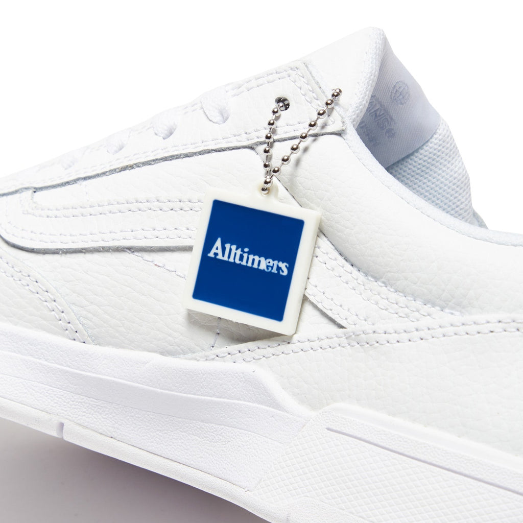 A white VANS tennis shoe with a blue tag on it.
