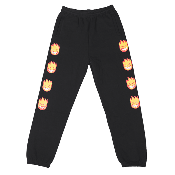 The DELUXE SPITFIRE Bighead Fill Sweatpants in black feature a repeating Bighead flame face design on the left leg. These stylish sweatpants come with an elastic waistband and cuffs.