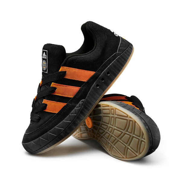 A pair of black and orange ADIDAS JAMAL SMITH ADIMATIC BLACK / ORANGE RUSH shoes on a white background.
