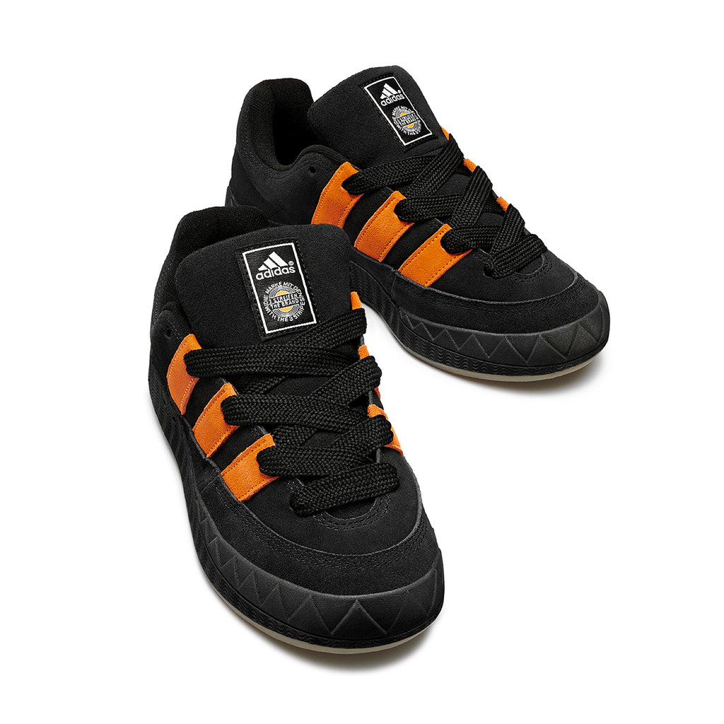A pair of black and orange Adidas Jamal Smith Adimatic sneakers on a white background.