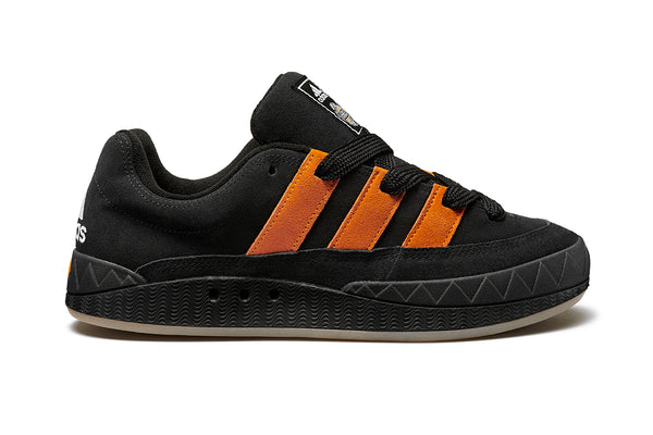 A black and orange ADIDAS JAMAL SMITH ADIMATIC BLACK / ORANGE RUSH sneaker with orange stripes.