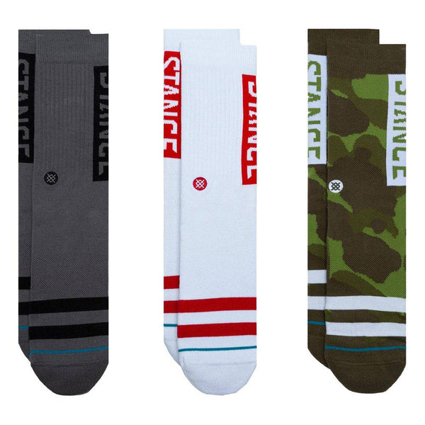 Three pairs of STANCE SOCKS THE OG 3 PACK CAMO LARGE with different designs: one with grey and blue stripes, another with white and red stripes, and a third with CAMO LARGE pattern.