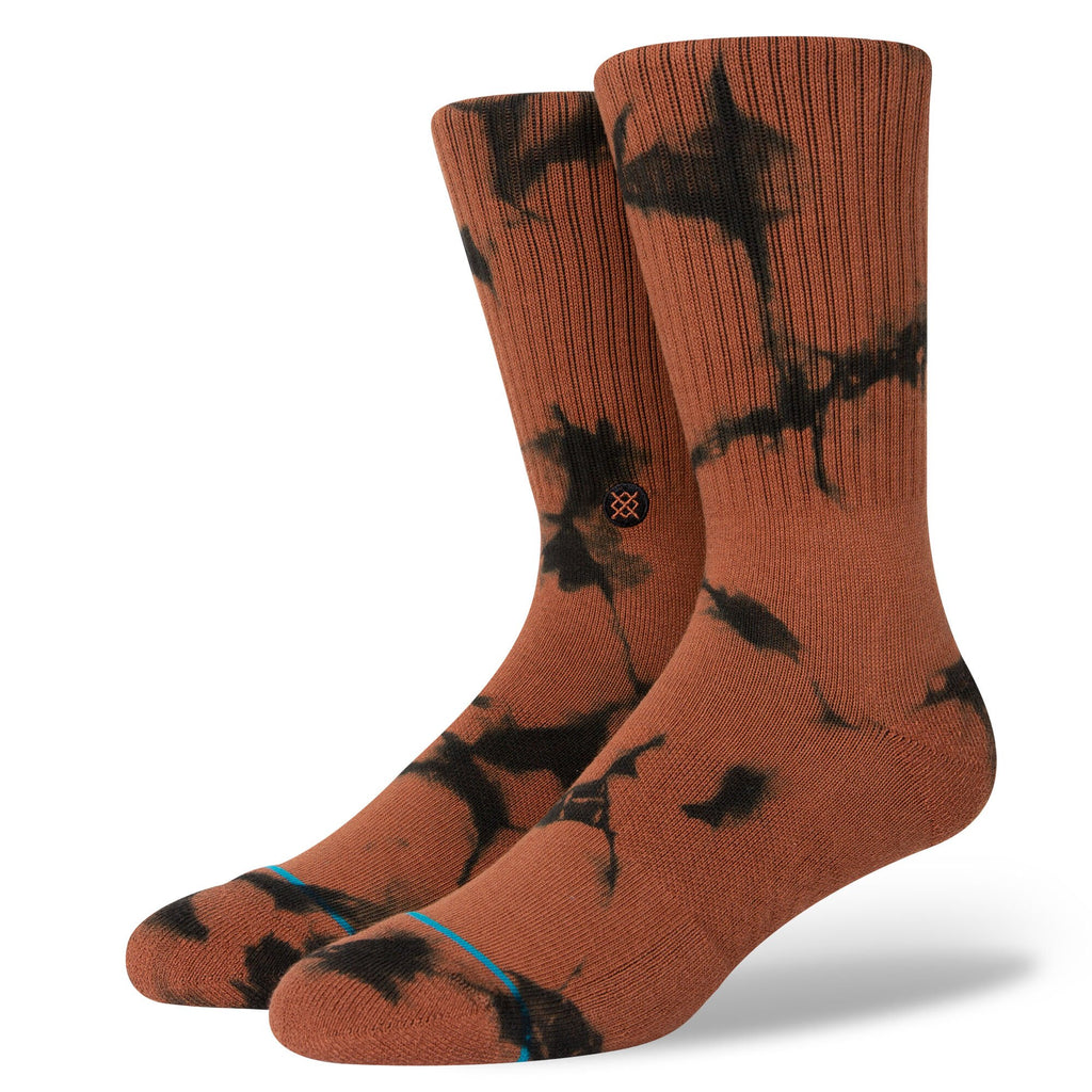 A pair of orange and black dyed tie-dye patterned Stance socks with a small logo on the side.