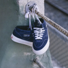 A pair of blue Vans Skate Half Cab Dress Blues sneakers, perfect for skateboarding, hanging on a railing.