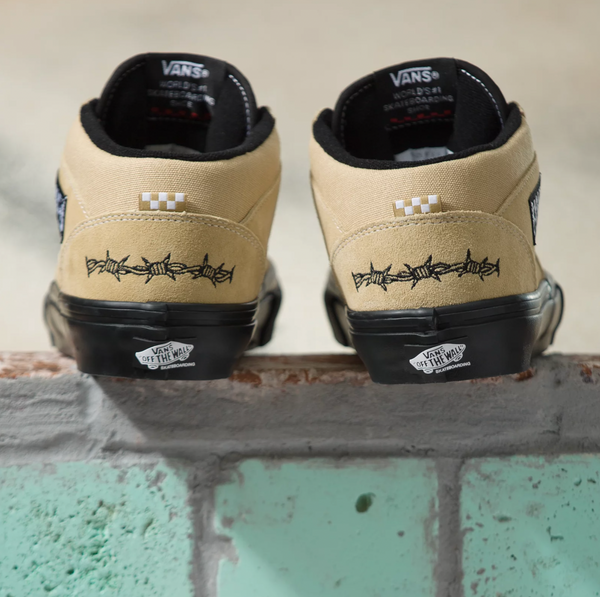 A pair of Vans Elijah Berle skate half cab beige sneakers skateboarding on a brick wall.