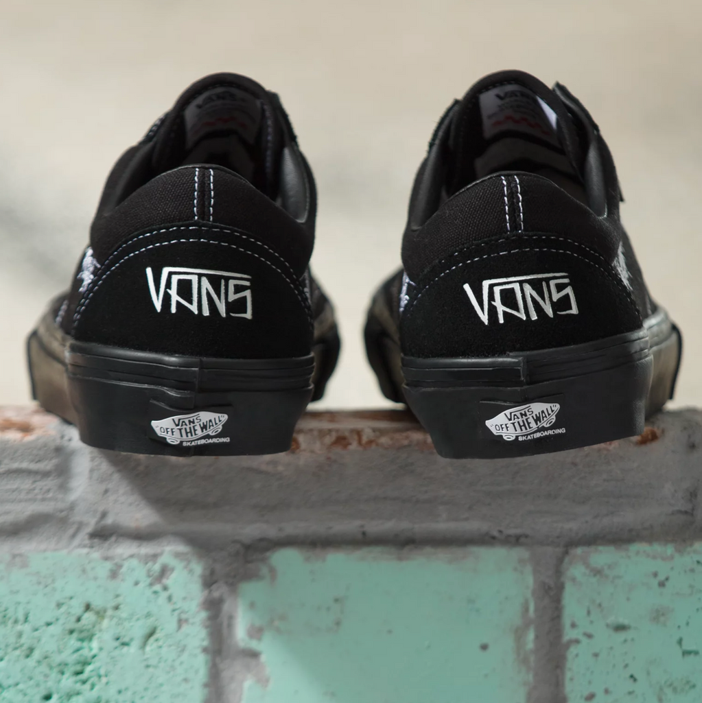 A pair of black and white Vans Elijah Berle Skate Old Skool sneakers featuring skater Elijah Berle on a brick wall.