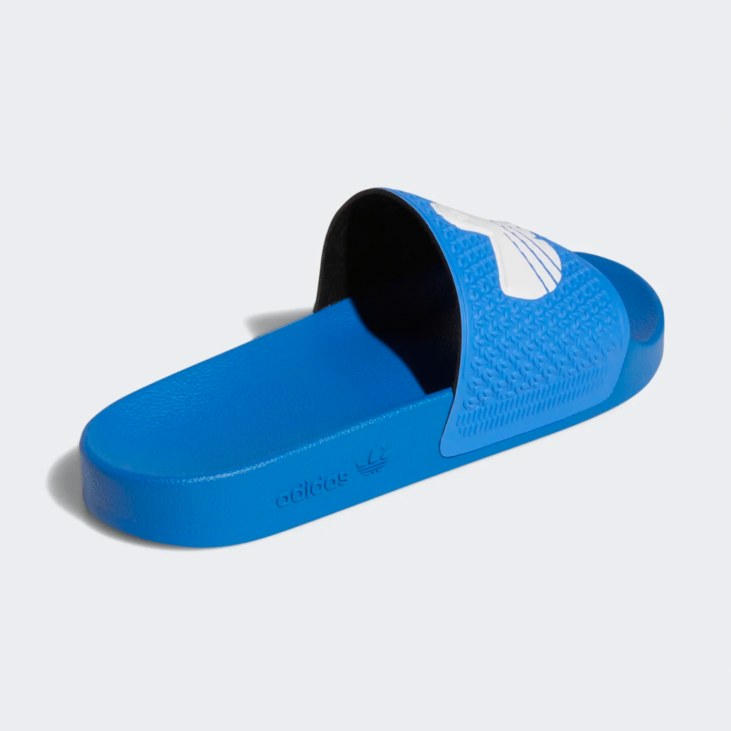 A pair of ADIDAS SHMOOFOIL BLUE BIRD/WHITE slippers with a white and black sole.