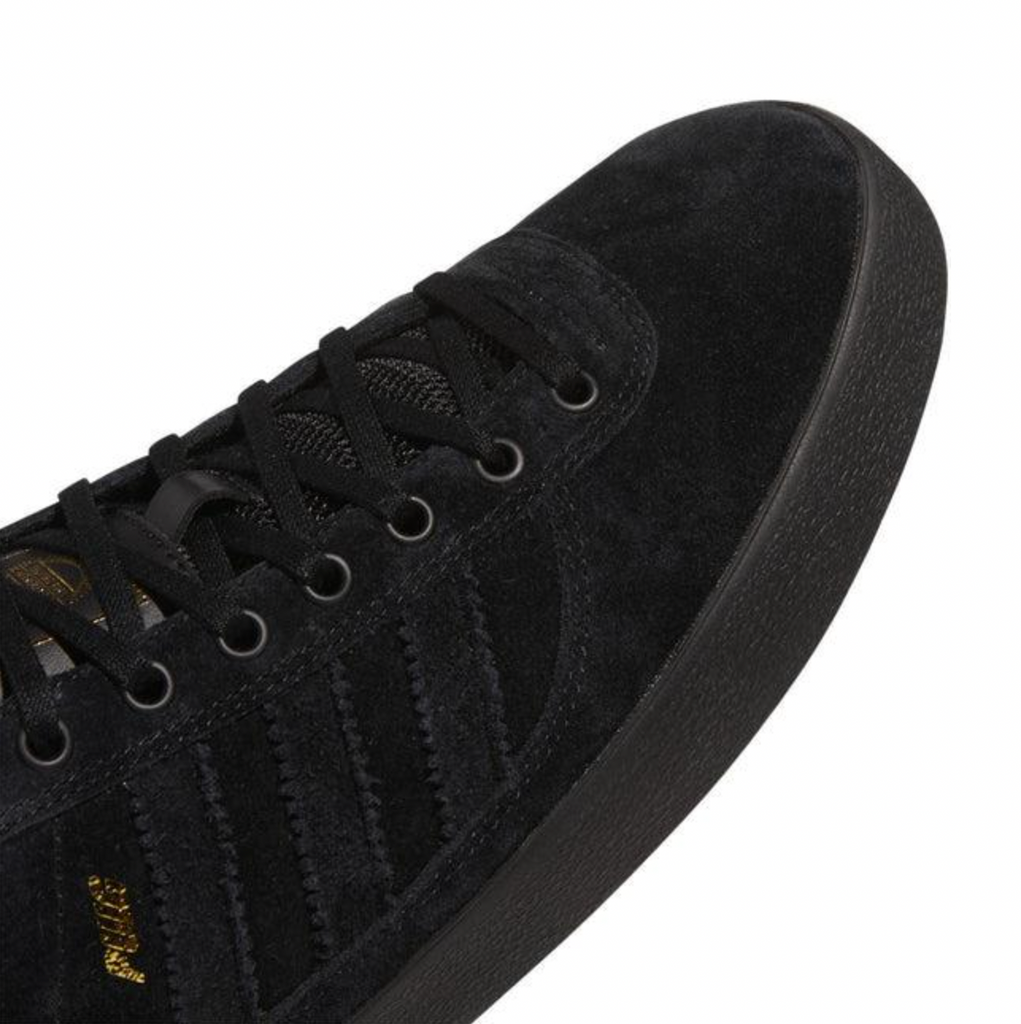 A pair of ADIDAS PUIG INDOOR BLACK / BLACK shoes with gold detailing.