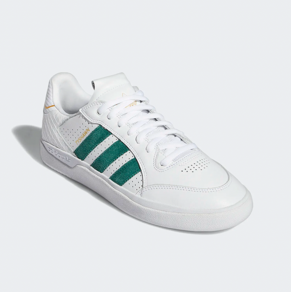 A pair of white and green ADIDAS TYSHAWN LOW FLAT WHITE / COLLEGIATE GREEN / METALLIC GOLD sneakers on a white background.