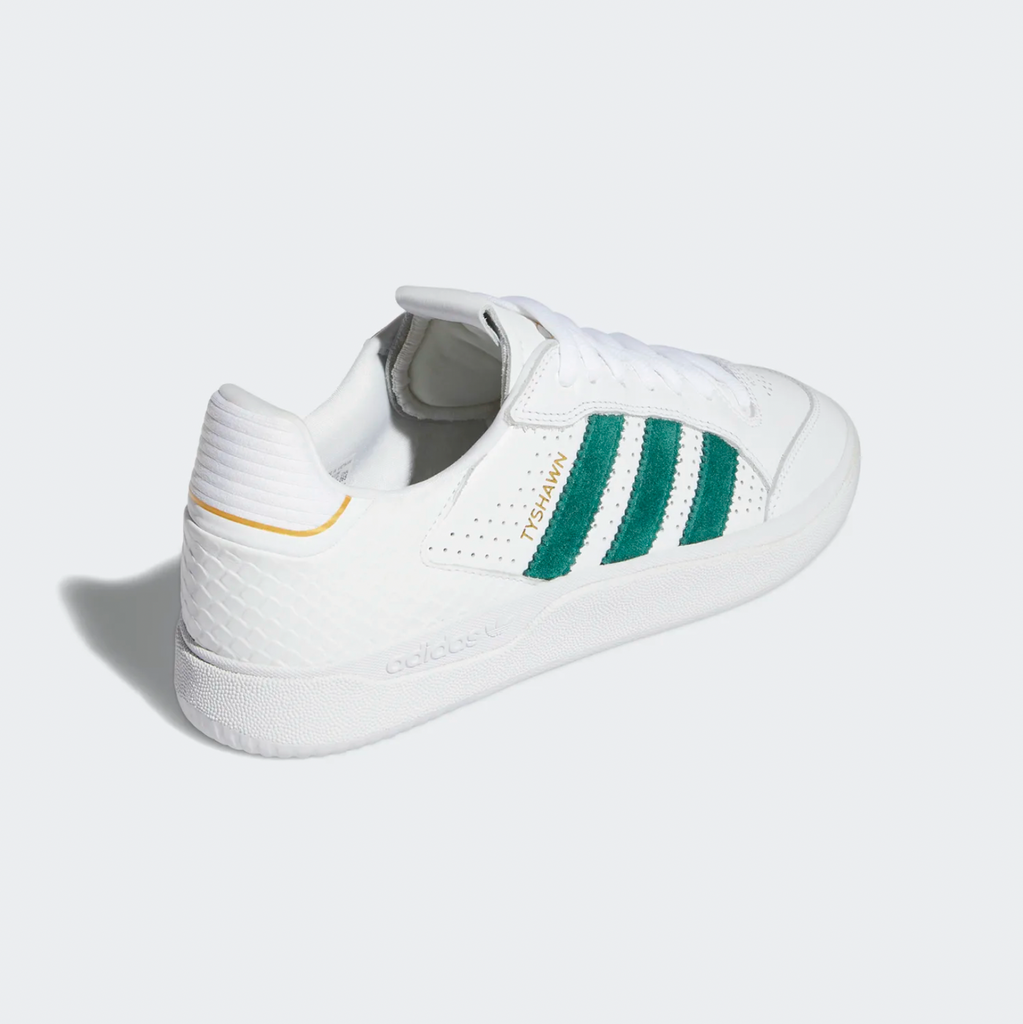 A white and green ADIDAS TYSHAWN LOW FLAT WHITE / COLLEGIATE GREEN / METALLIC GOLD sneakers on a white background.