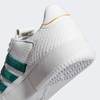 A close up of a white and green ADIDAS TYSHAWN LOW FLAT WHITE / COLLEGIATE GREEN / METALLIC GOLD tennis shoe.