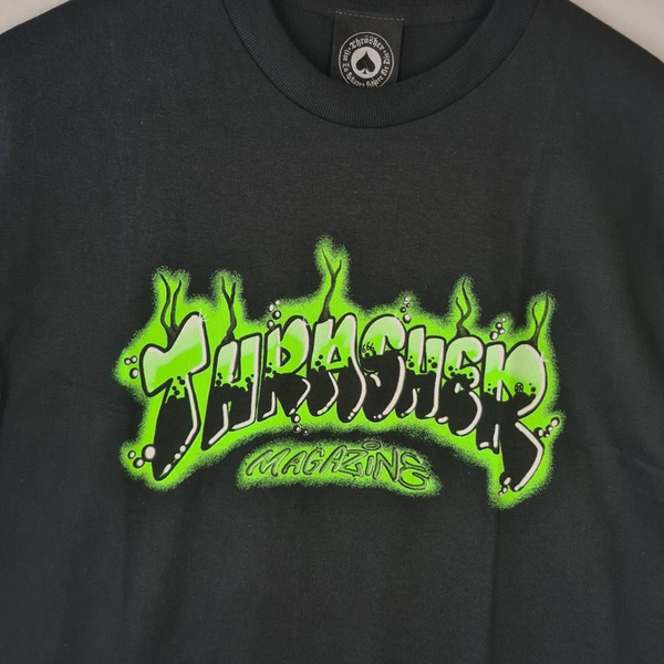 The THRASHER AIR BRUSH TEE BLACK showcases a green and white graffiti-style "THRASHER Magazine" logo on the front.