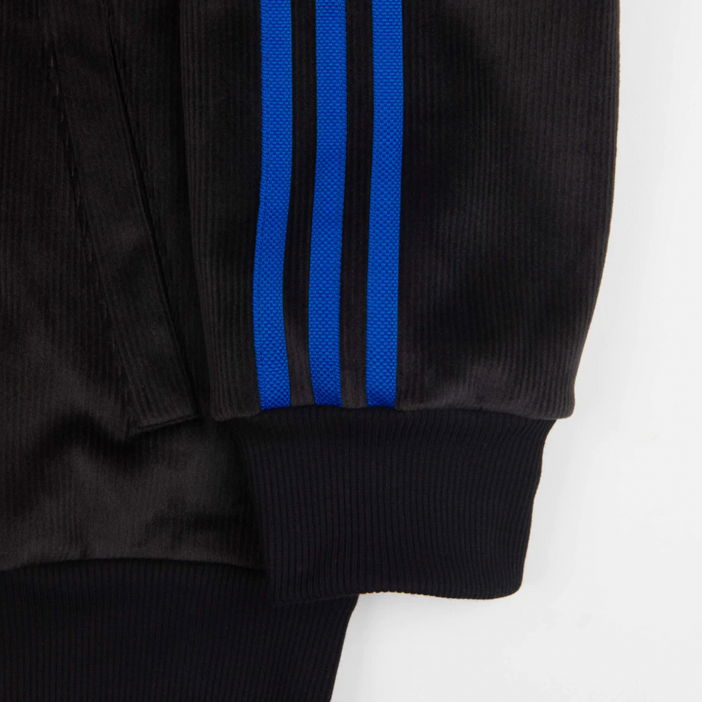 A close up of an ADIDAS TYSHAWN VELOUR JACKET with blue stripes.