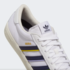 A white ADIDAS Nora Grey One sneakers with a Shadow Navy and Gold stripe.